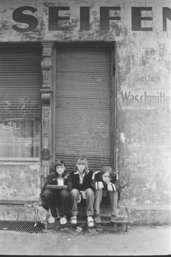 Children sit on the threshold of a closed shop in Oderbergerstrasse, 1984, Prenzlauer Berg, Berlin, GDR, Germany, Europe