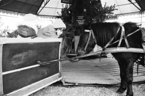 Children in a horse-drawn carousel at the Christmas market on Alexanderplatz, 1983, Mitte, Berlin, GDR, Germany, Europe